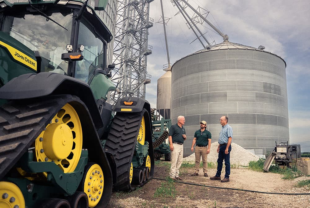 Farm-Equipment farm team in front of farm equipment and grain bin
